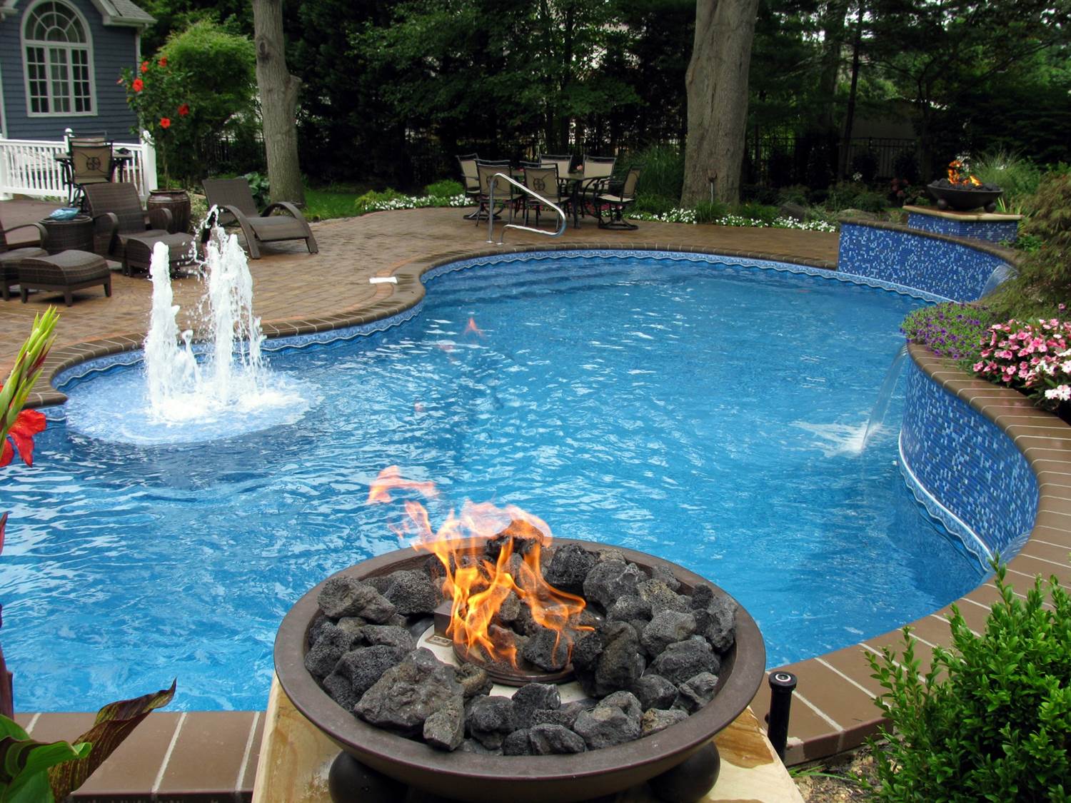 a swimming pool with a fire pit and a fountain