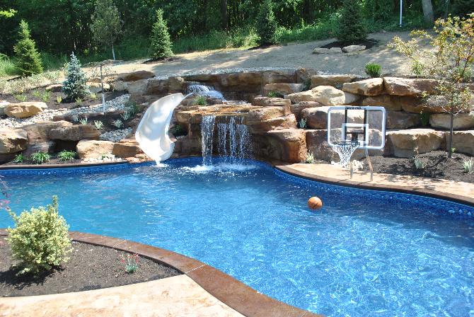 a large swimming pool with a water slide and a basketball hoop .