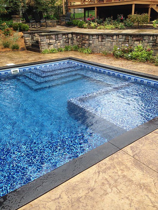 a large swimming pool with stairs and a stone wall