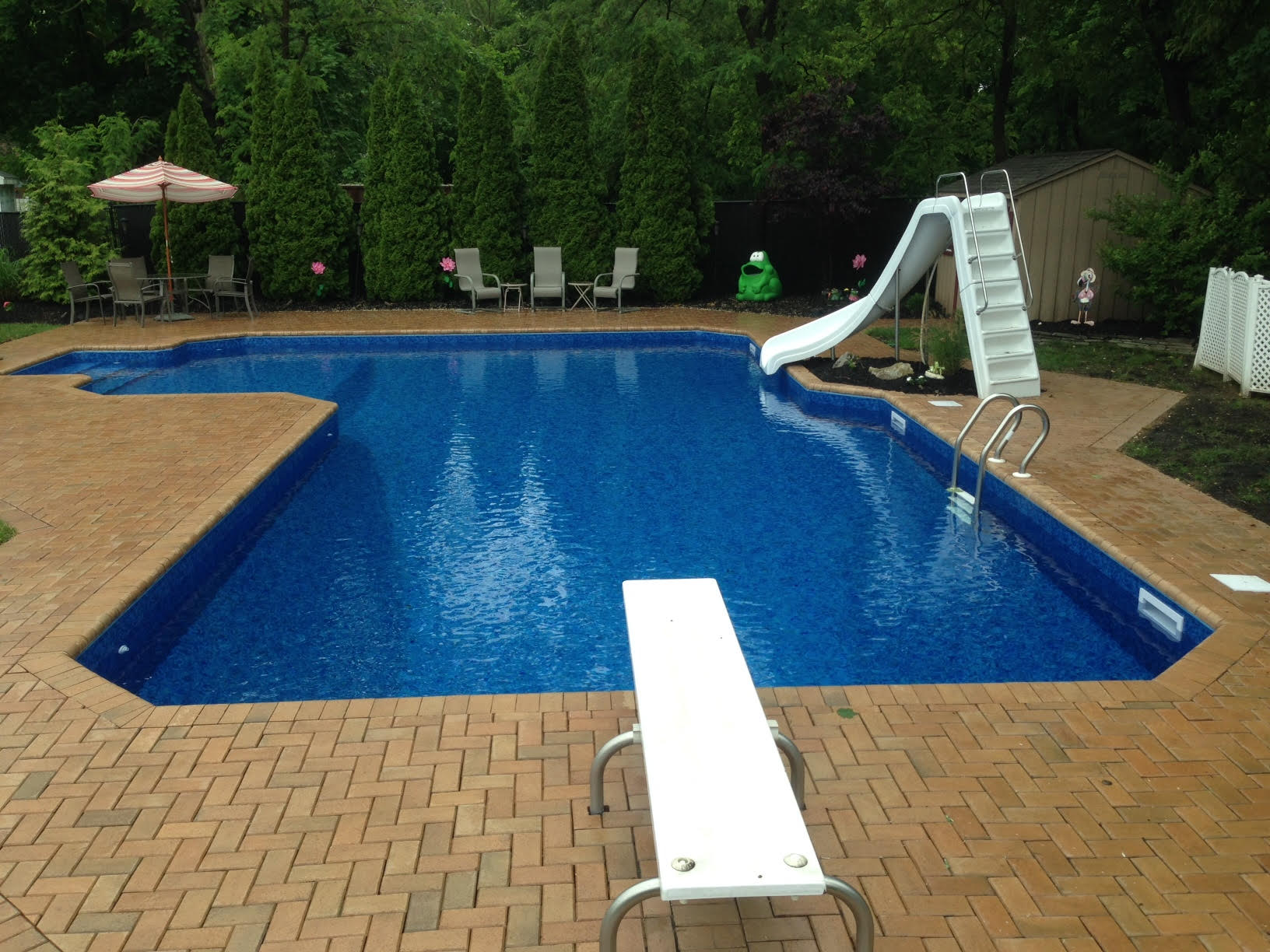 a large swimming pool with a slide and diving board in suffolk county