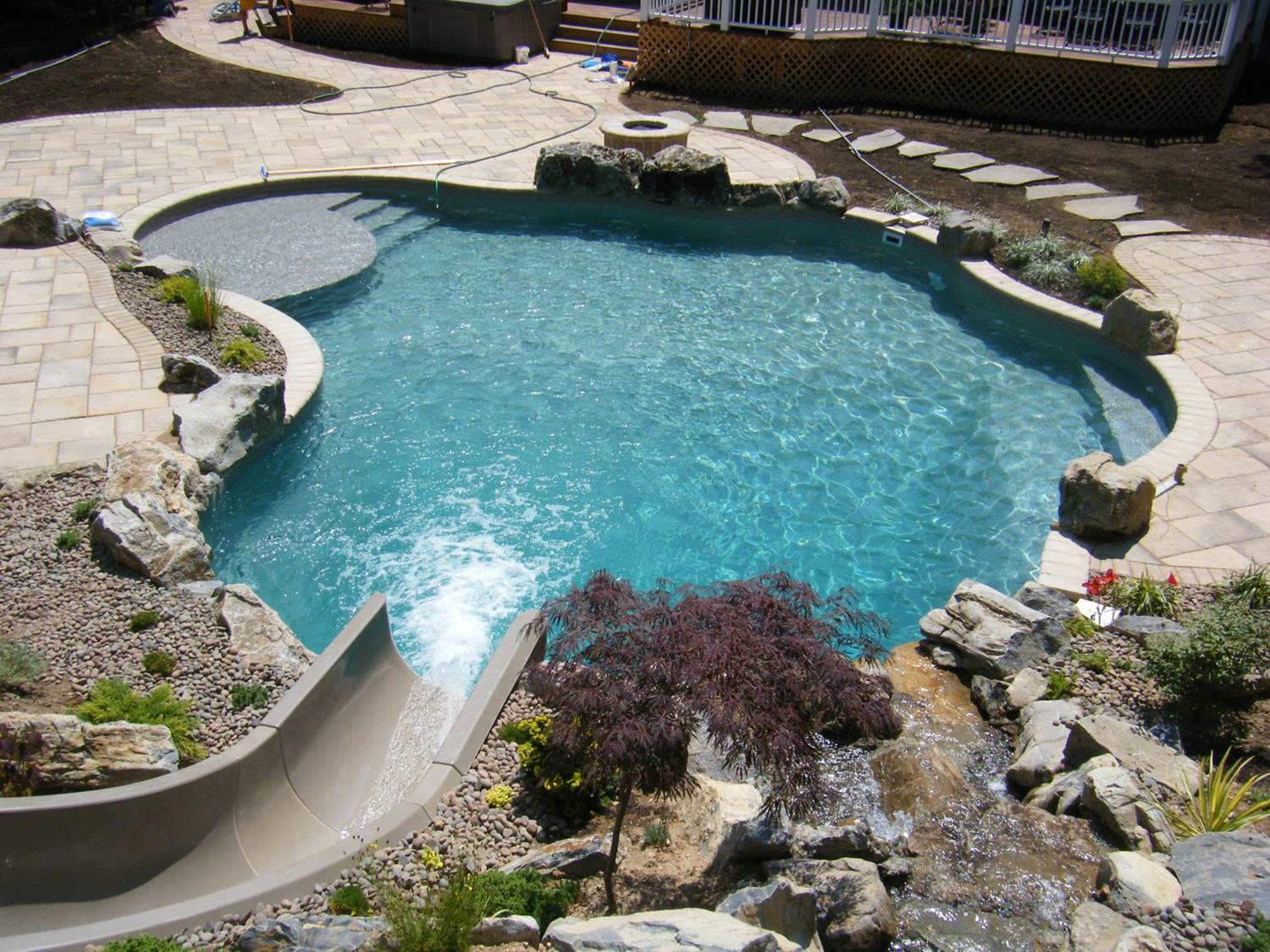 a large swimming pool surrounded by rocks and a slide
