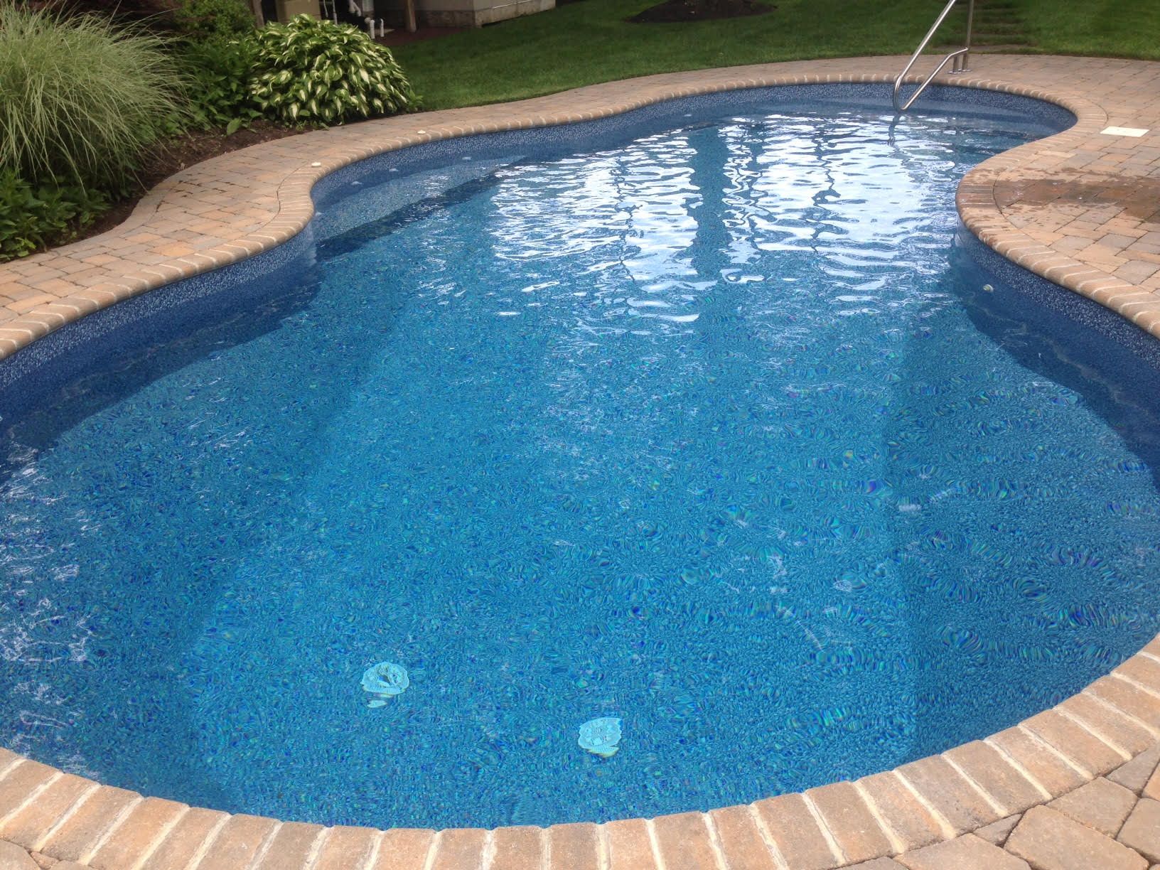 a large blue swimming pool with a brick border