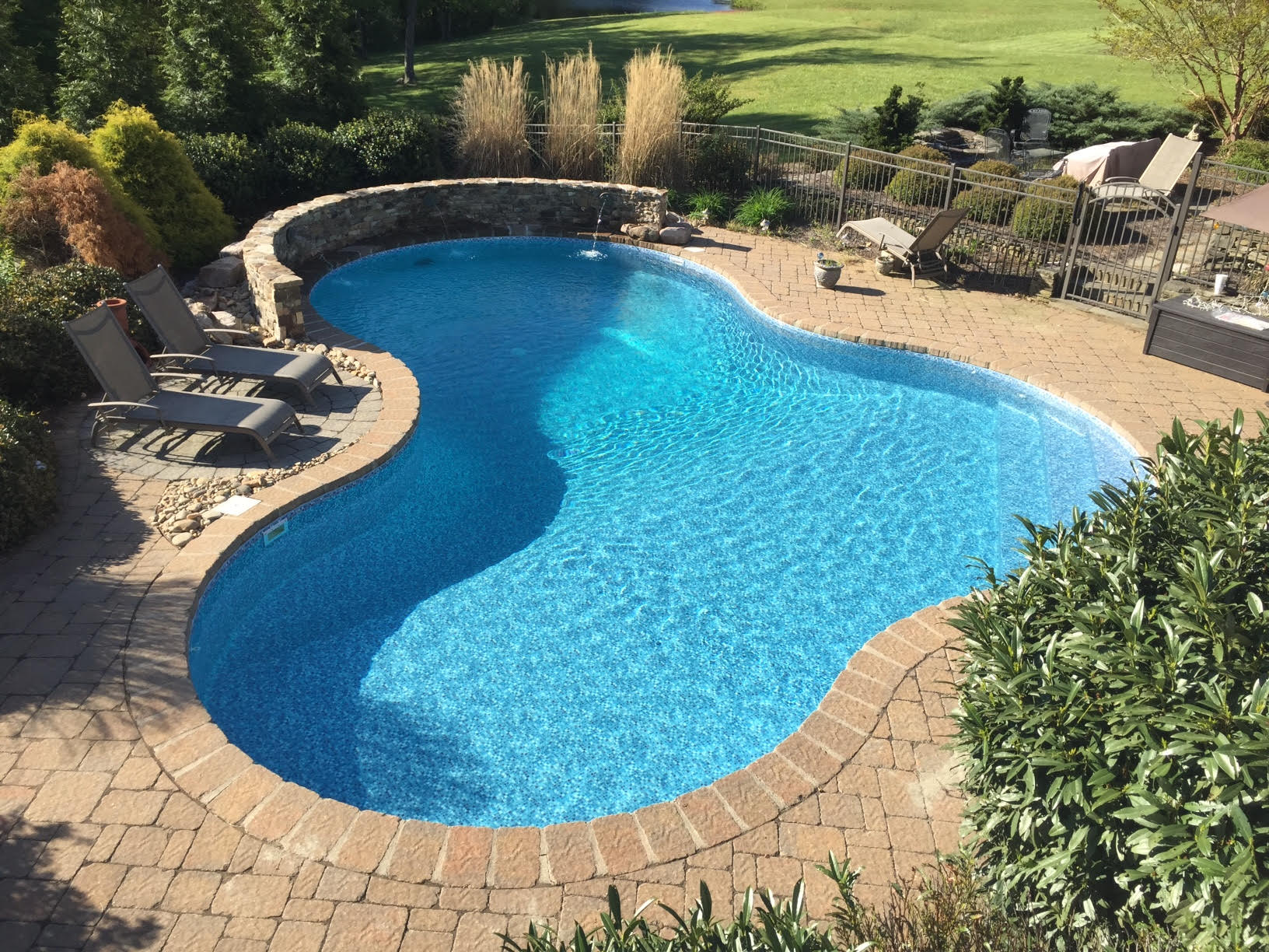 a large swimming pool surrounded by chairs and a stone wall