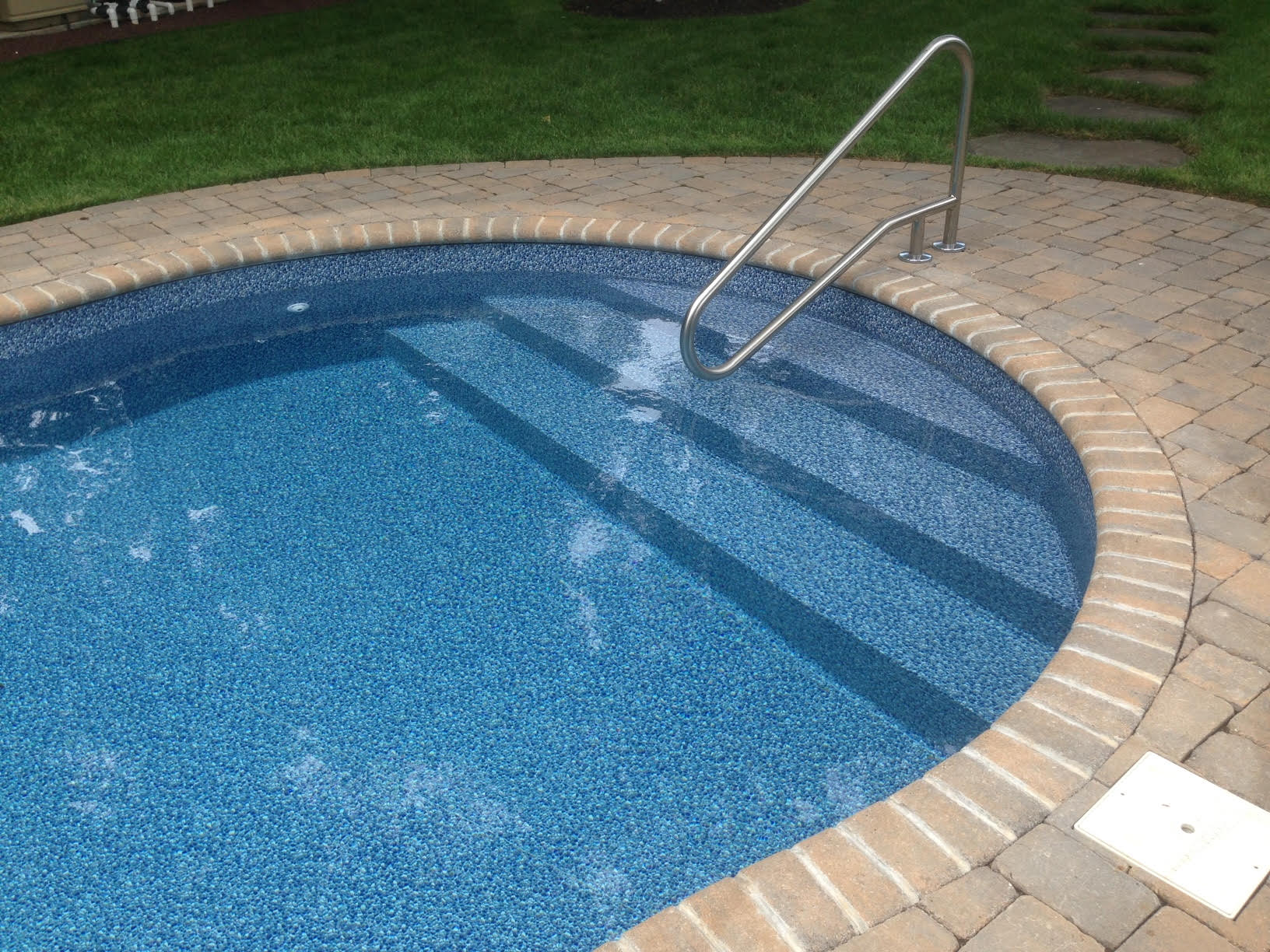 a swimming pool with stairs and a brick border