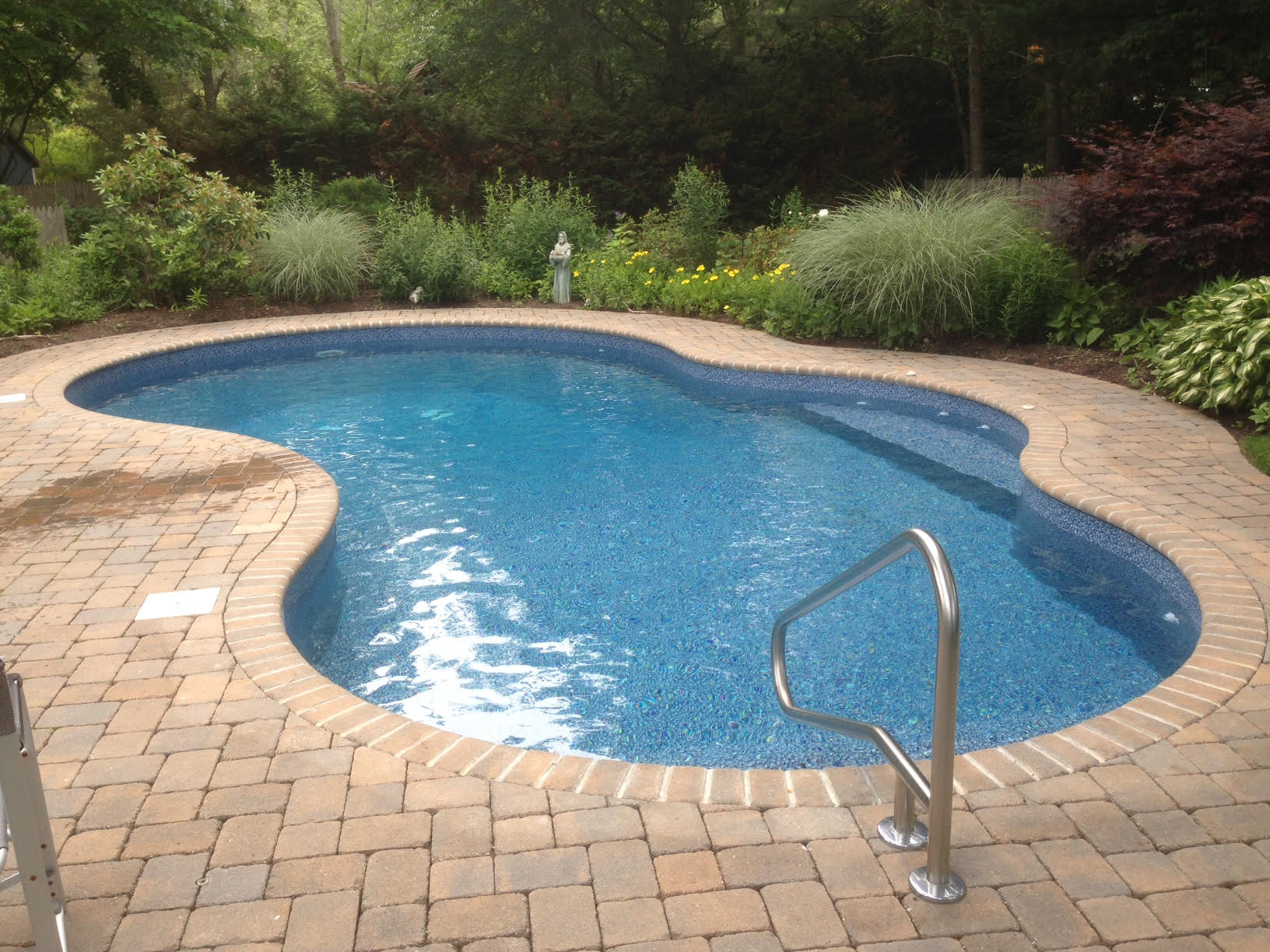 a large swimming pool is surrounded by bricks and plants