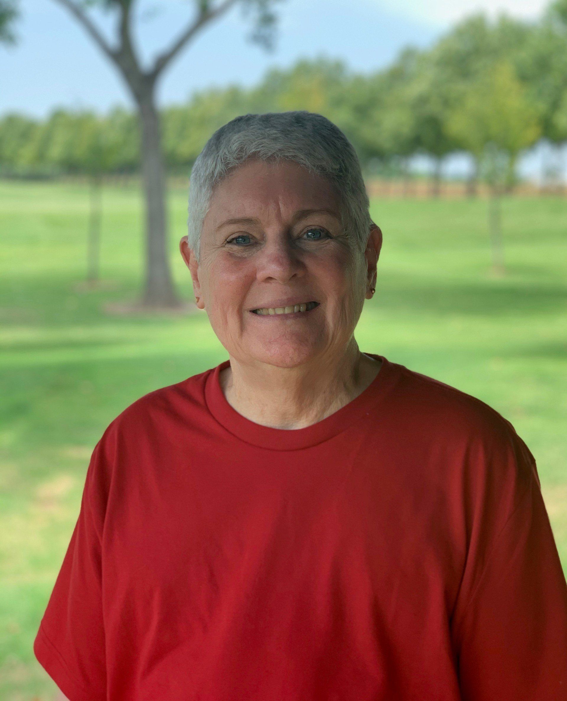 A woman in a red shirt is smiling for the camera
