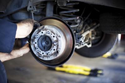 A man is fixing a brake on a car in a garage.