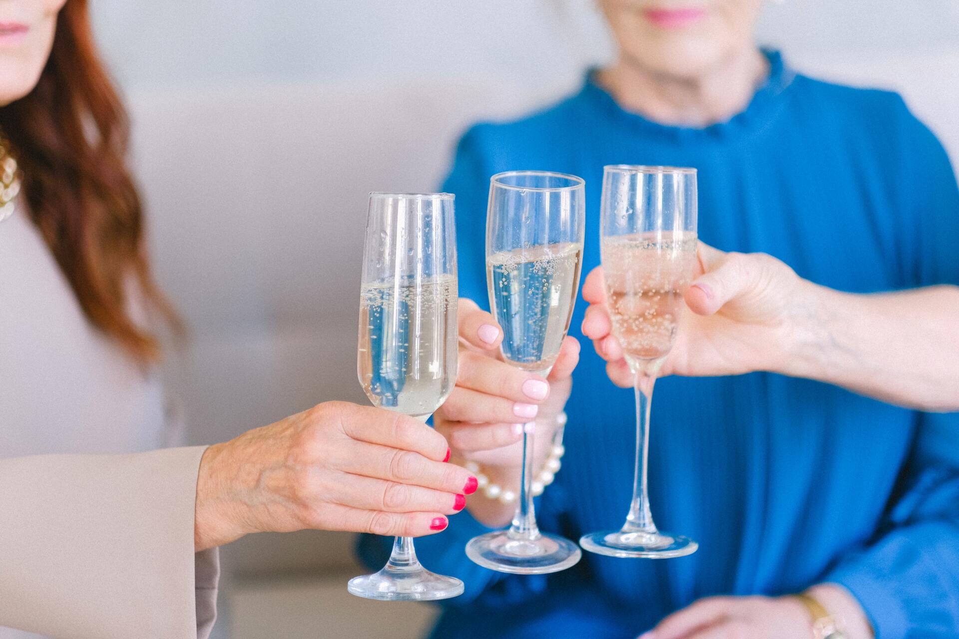 Two women are toasting with champagne glasses while sitting on a couch.