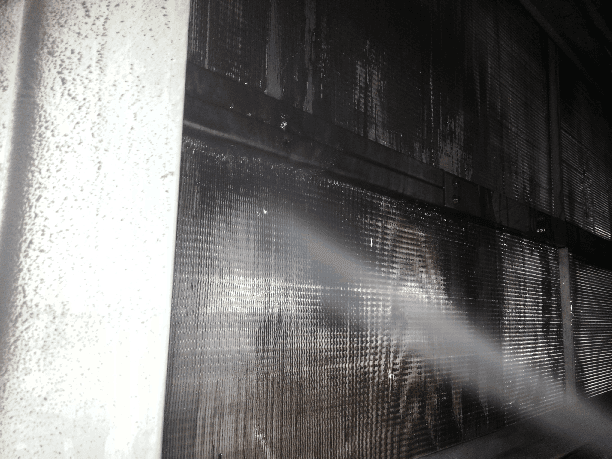 a person is cleaning a condenser coil with a high pressure washer .