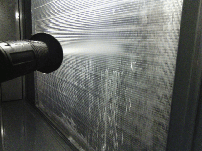 a person is spraying water on a condenser unit