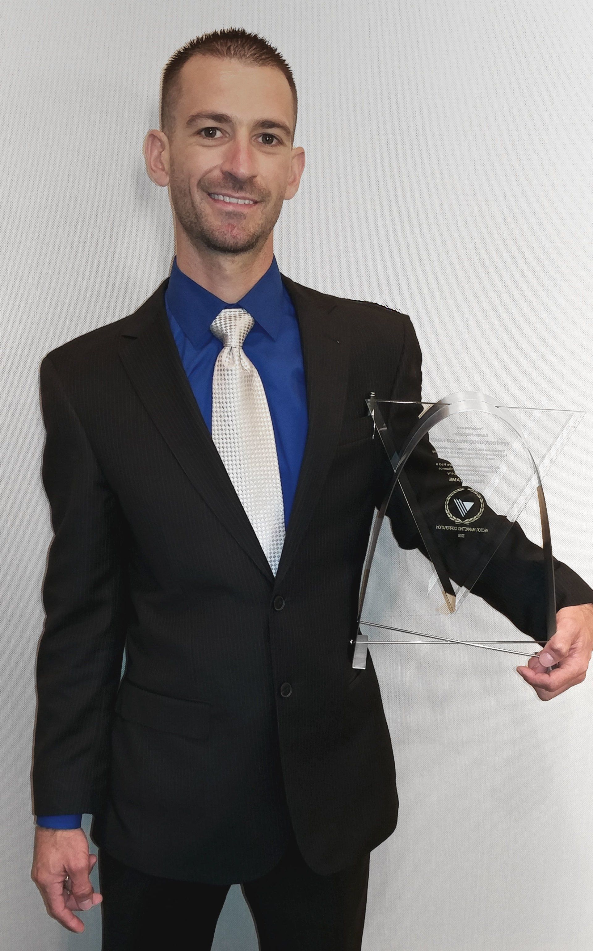 A man in a suit and tie is holding a trophy