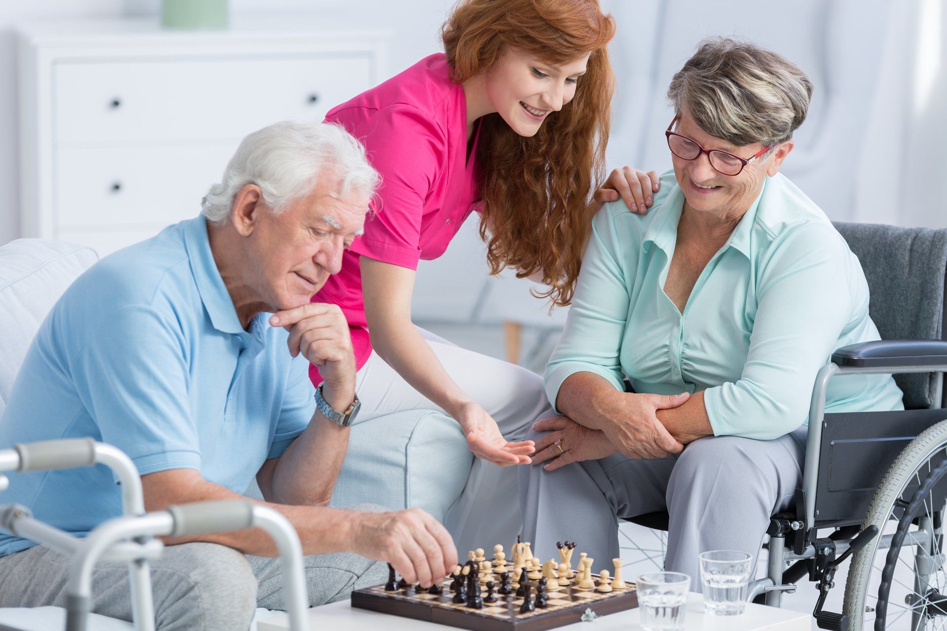 Une femme joue aux échecs avec deux personnes âgées.