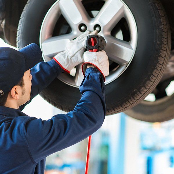 A Mechanic Screwing A Wheel — Wayne Boylett Mechanical in Cairns, QLD A Mechanic Screwing A Wheel — Wayne Boylett Mechanical in Cairns, QLD
