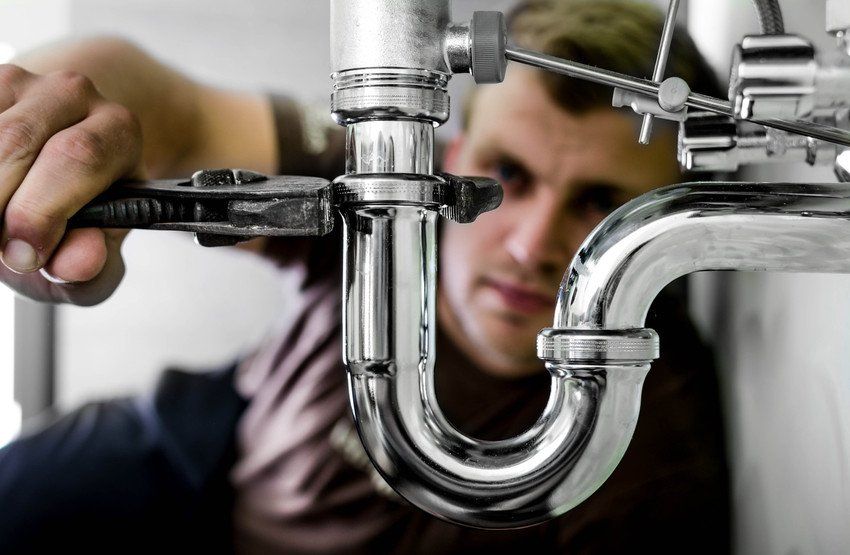 Plumber fixing faucet close-up representing plumbing services and repairs.
