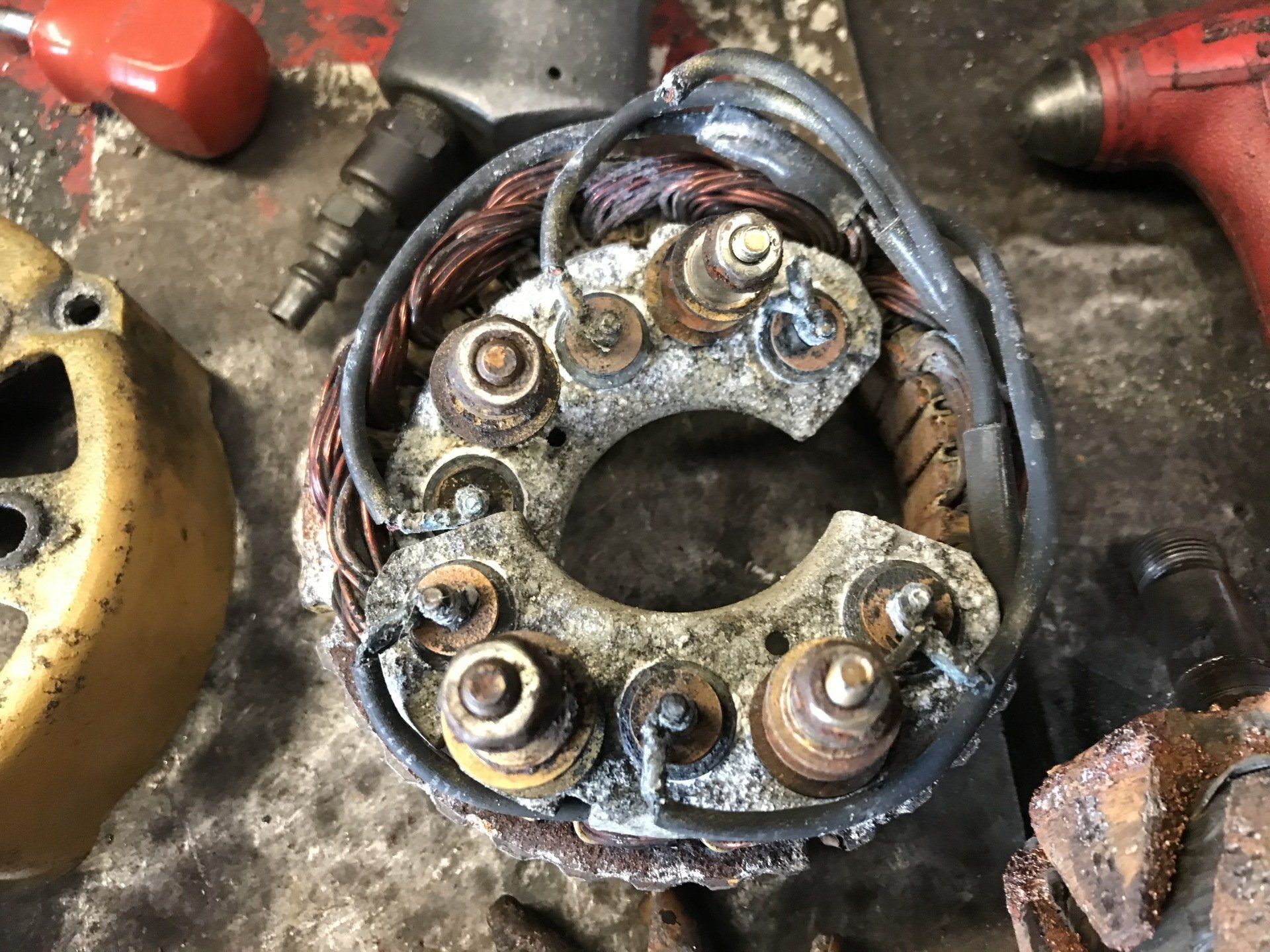 Close-up of a dirty electrical motor armature with copper windings and bolts on a workbench