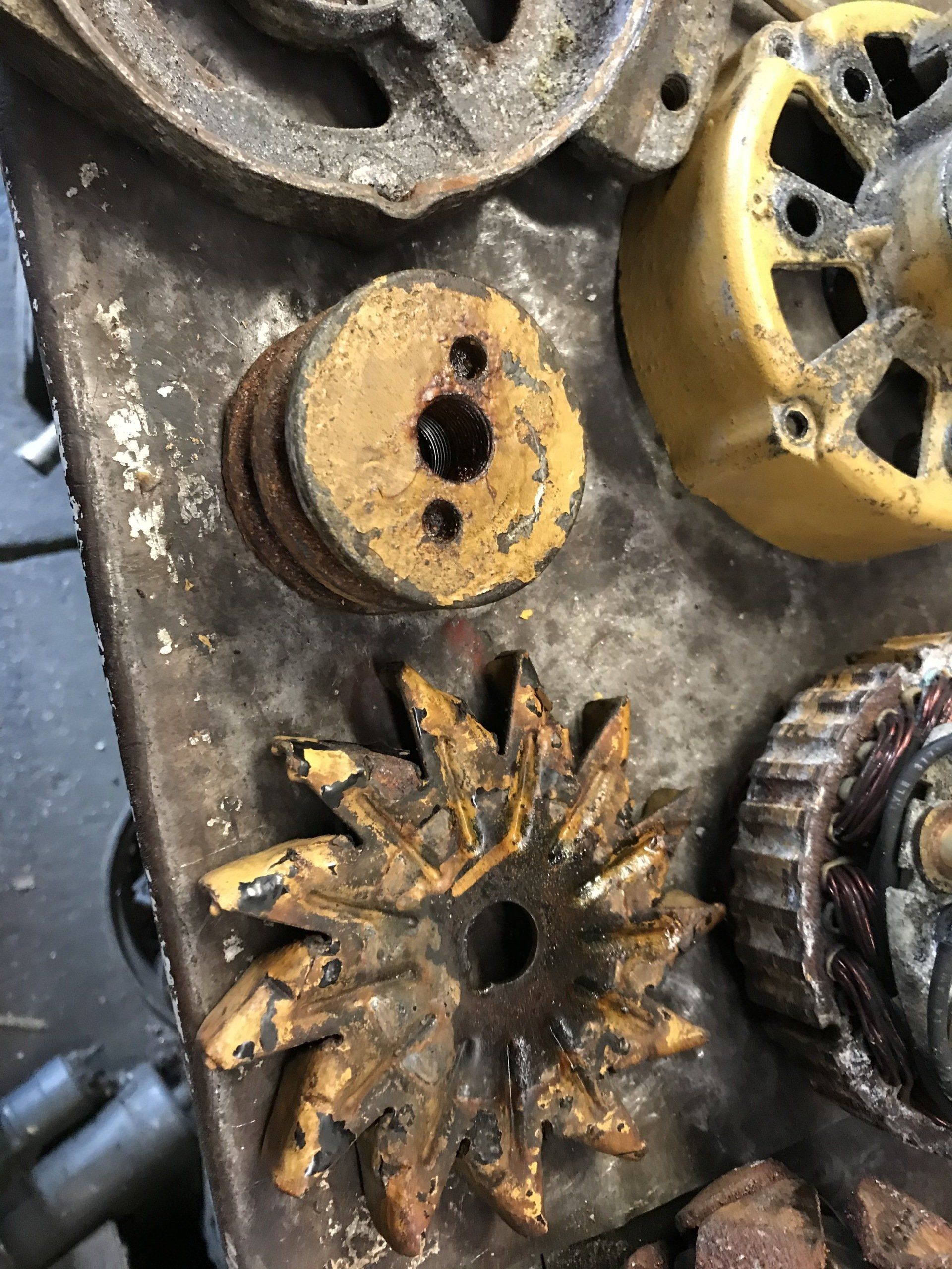 Rusty metal gears and circular parts arranged on a dusty surface, yellow paint chipped and worn