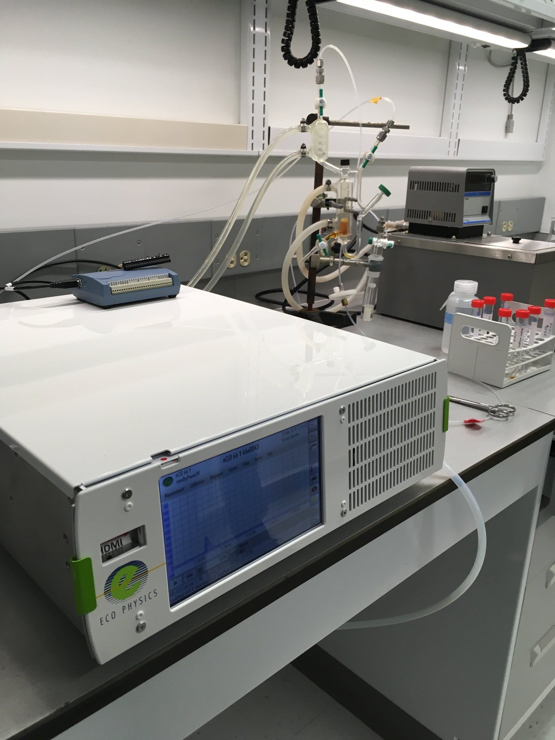 A white box with a blue screen sits on a desk in a lab
