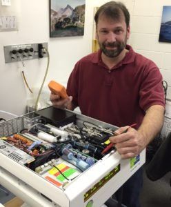 A man in a red shirt is holding a remote control