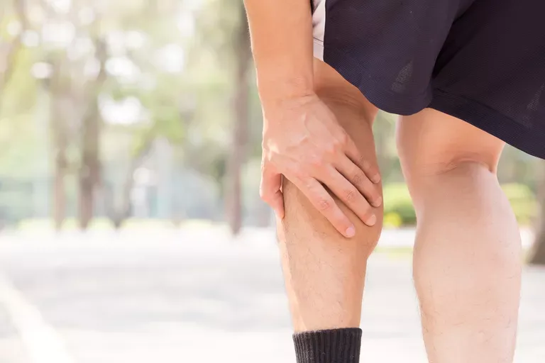 A person is holding their leg in pain.