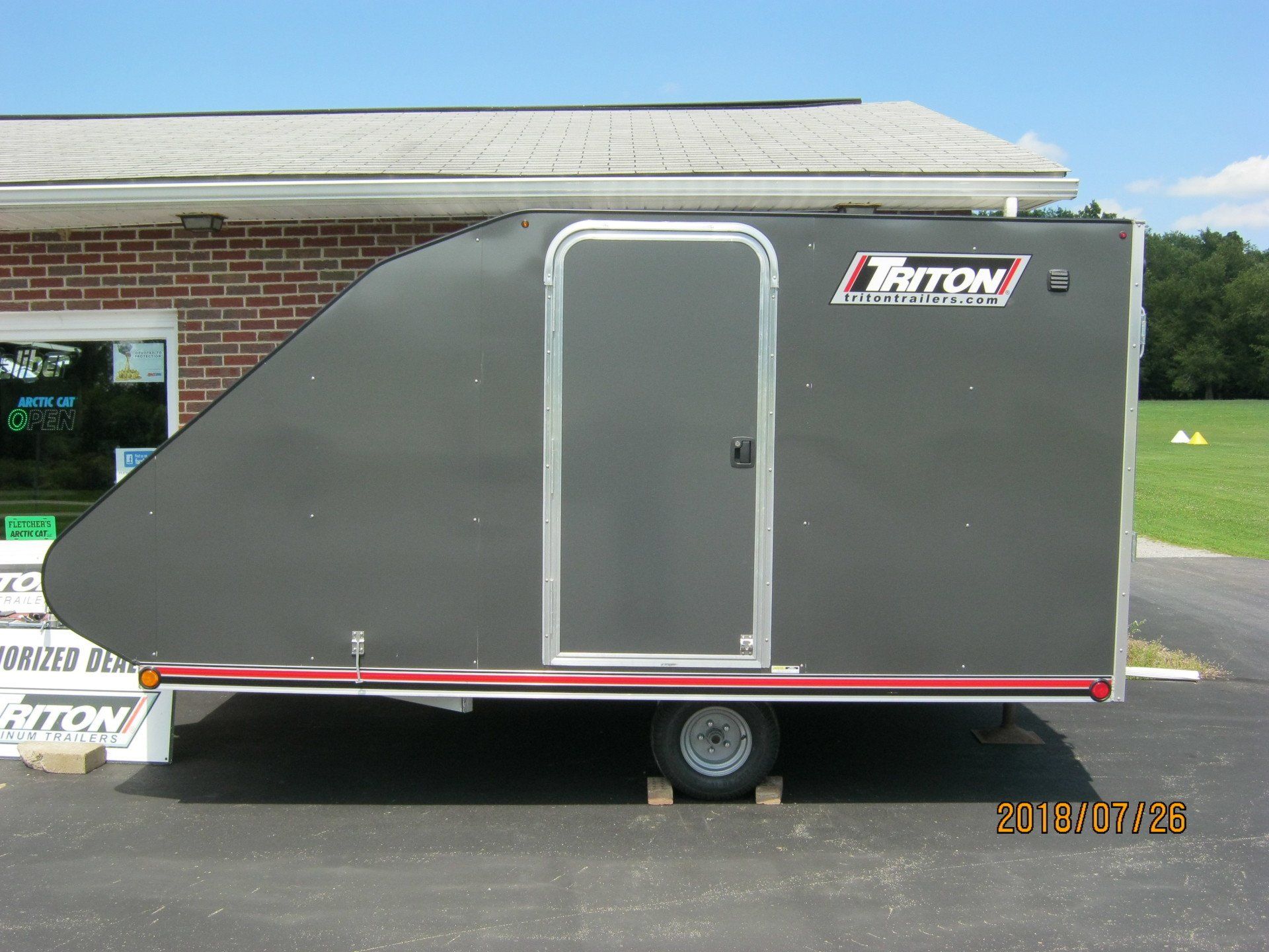 A triton trailer is parked in front of a brick building