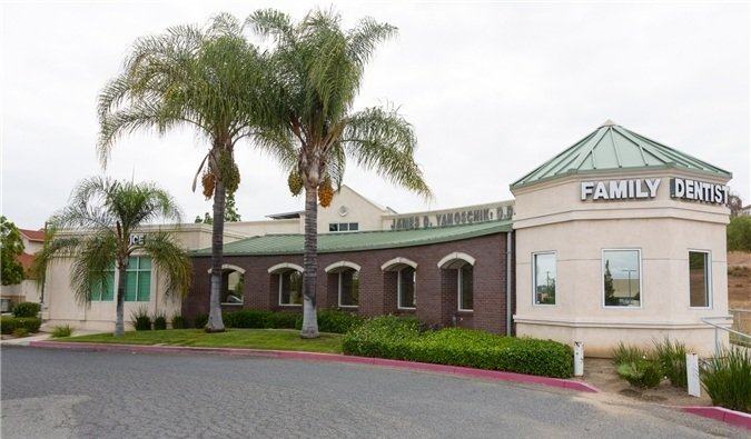 Exterior of a family center building with palm trees. Beige building with