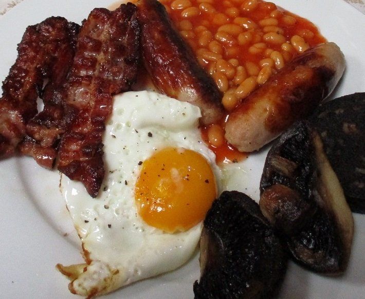 A hearty and delicious cooked breakfast, with sausages, fried egg, beans, mushrooms, black pudding, white pudding and bacon