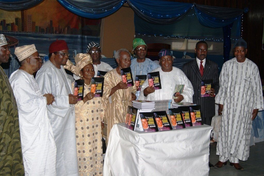 A group of people standing around a table with books on it
