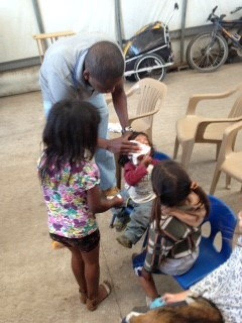 A group of children are sitting in chairs and a man is standing around them