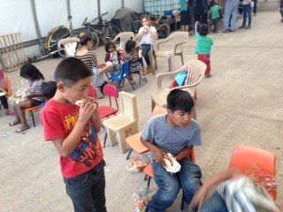 A boy in a red shirt is eating a hot dog