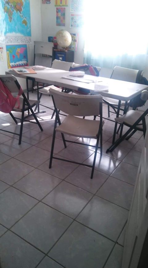 A classroom with a table and chairs and a globe on the wall.