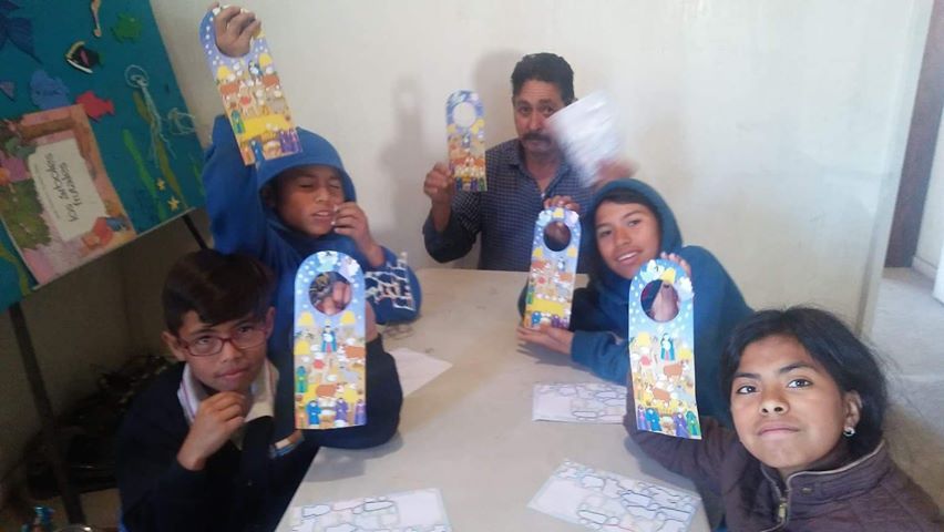 A group of children are sitting at a table holding up cards.