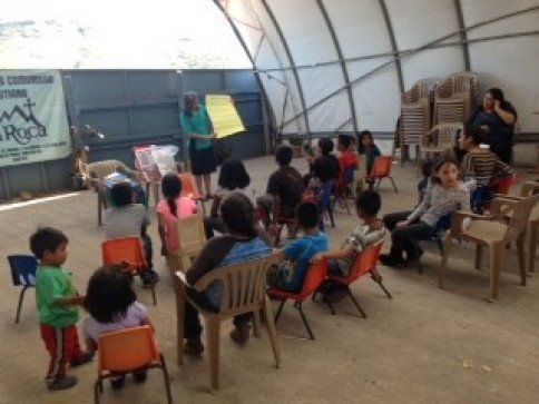 A group of children are sitting in chairs in front of a sign that says rock