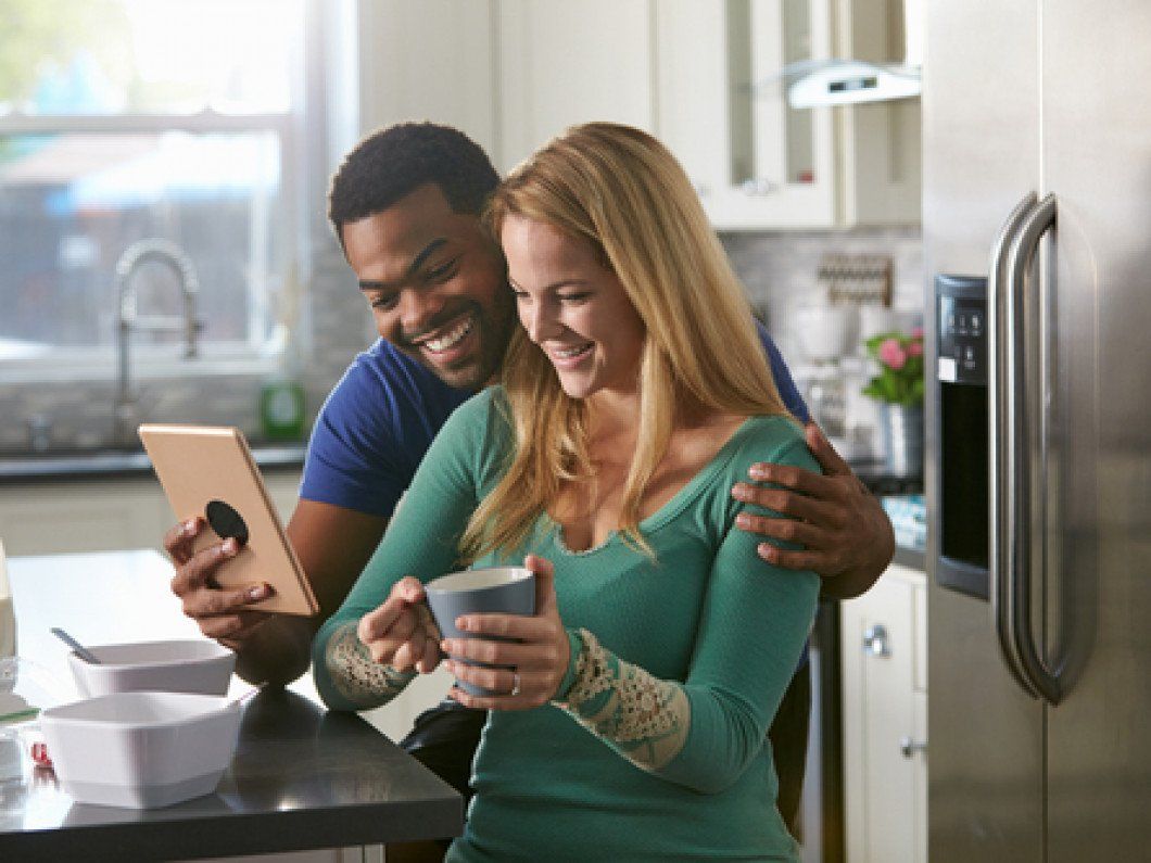 Mixed race couple looking at a tablet computer together in kitchen