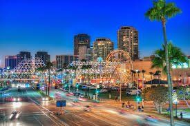 Night view of Long Beach skyline with illuminated Ferris wheel and palm trees.