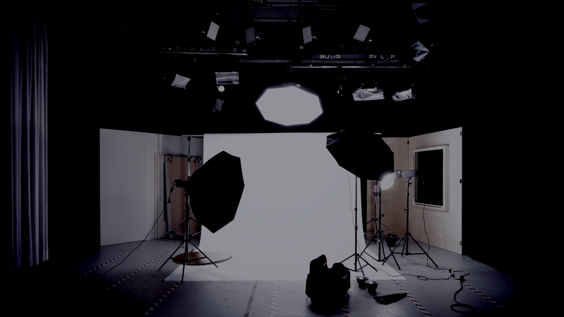 Photo studio with white backdrop and multiple lights.