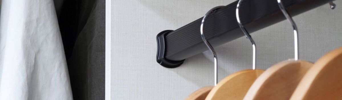 A close up of a closet with clothes hanging on a rack.