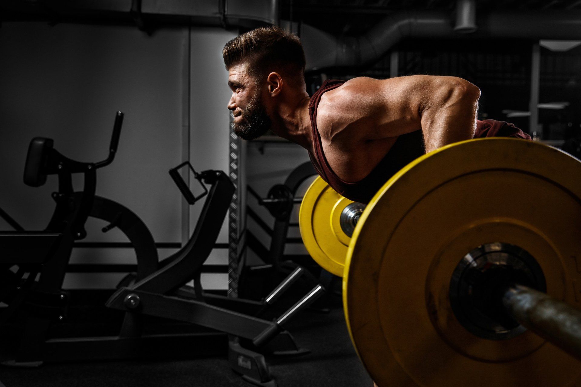 A man is lifting a barbell in a gym.