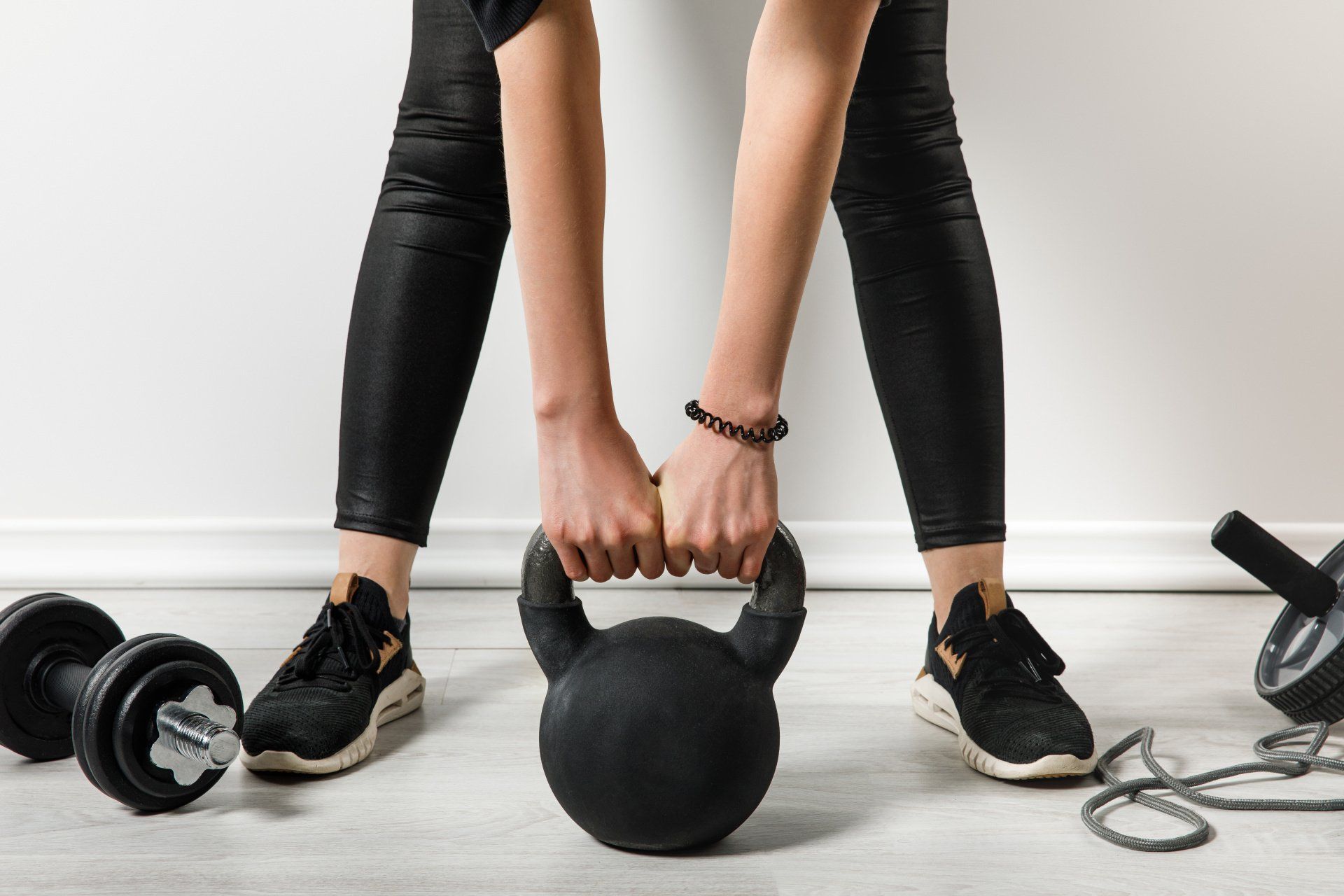 A woman is lifting a kettlebell in a gym.