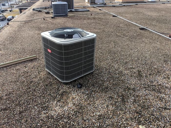 HVAC unit on a gravel-covered rooftop. Other units and building features are visible in the background.