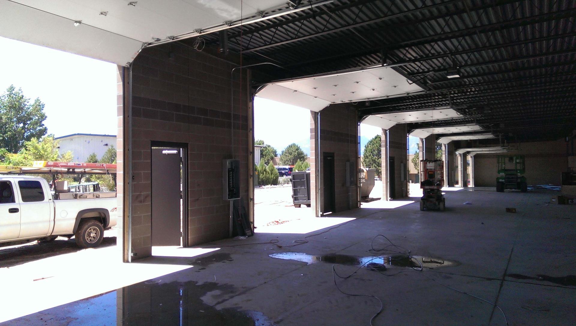 Large commercial garage space with multiple open bay doors, ideal for garage door opener installation in Colorado.