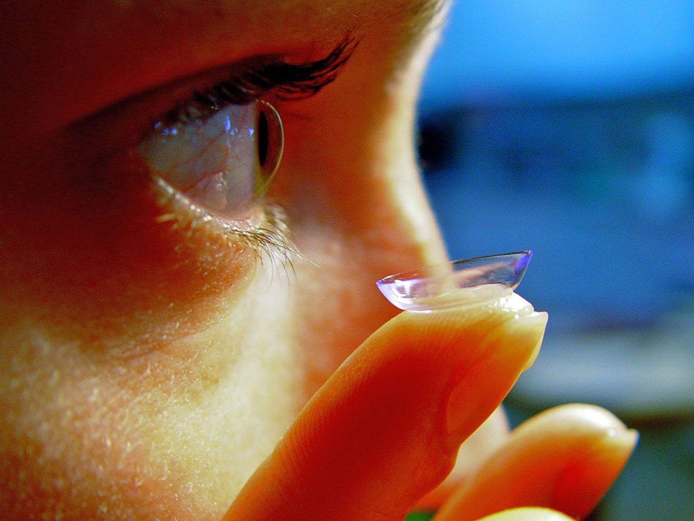 A close up of a person holding a contact lens on their finger.