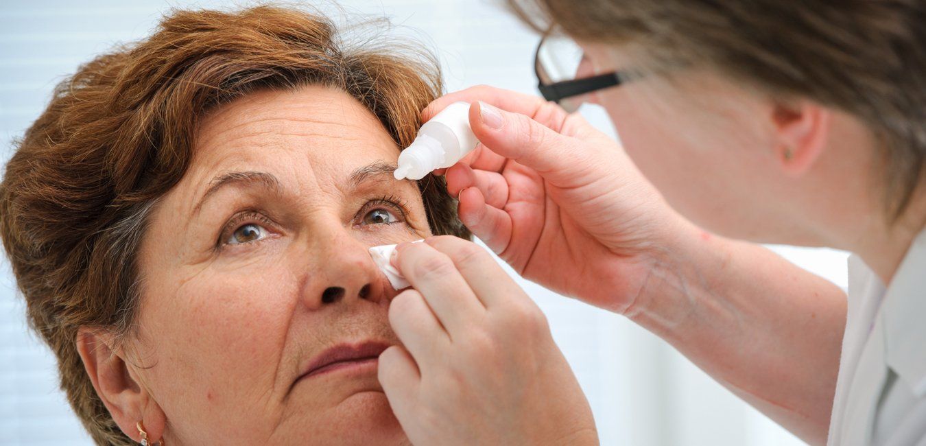 A doctor is applying eye drops to an older woman 's eye.
