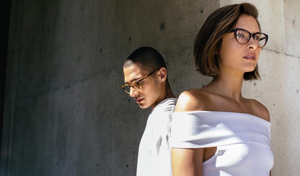 A man and a woman wearing glasses are standing next to each other.