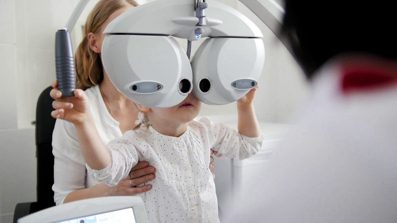 Child sitting on adult lap during eye exam