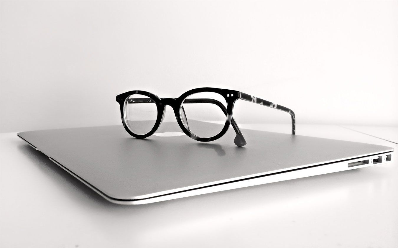 A pair of glasses is sitting on top of a laptop computer.