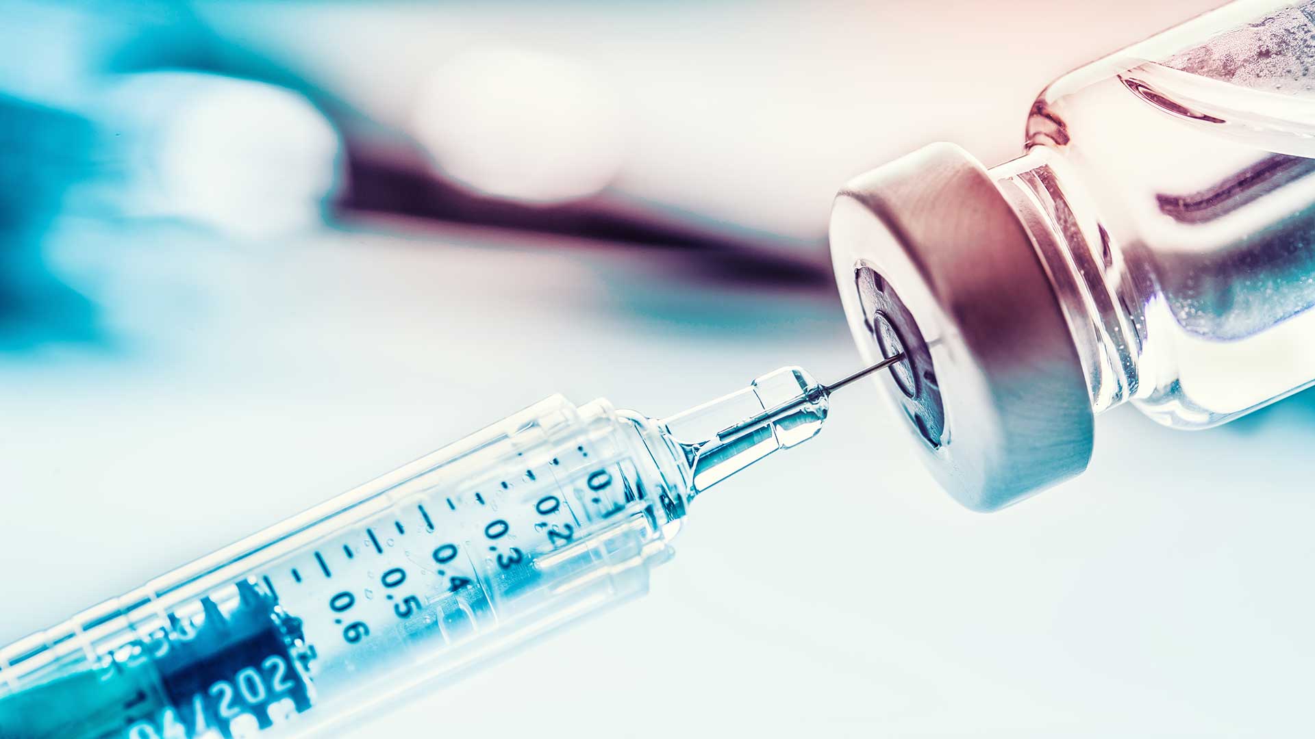 En sprøjte er ved at blive indsat i en flaske vaccine.