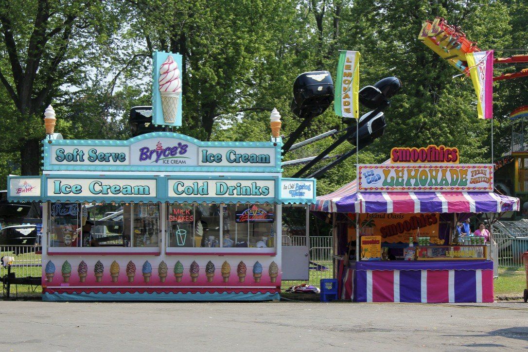 Several ice cream stands are lined up in a parking lot