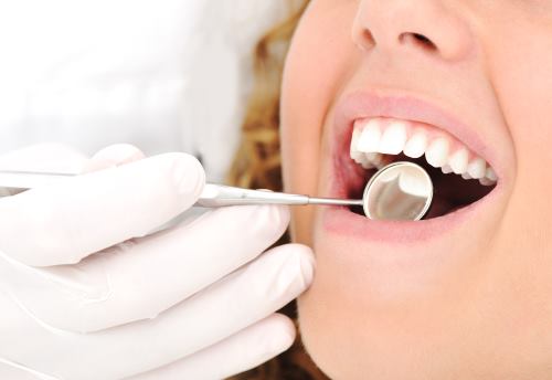 mano del dentista che controlla la bocca di una paziente