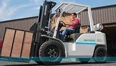Forklifts — Worker Driving A White Forklift Outside The Warehouse In Manorville, NY