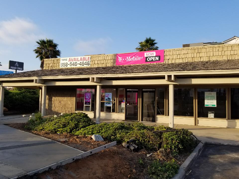 A T-Mobile store open, located in a building with a tan roof and beige facade, and a 